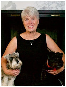 A woman holding two dogs in her arms.