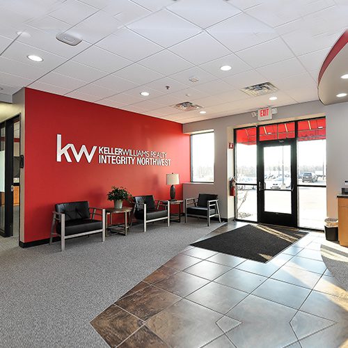 A lobby with two chairs and a red wall.